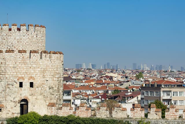 A historic stone tower overlooking the bustling skyline of Istanbul, showcasing a blend of ancient and modern architecture.