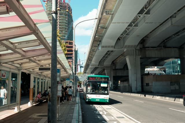 Urban scene capturing a bus under an elevated highway in Taipei City, Taiwan.