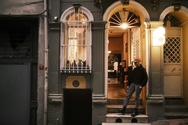 A person standing at the entrance of an old-style building, showcasing urban lifestyle.