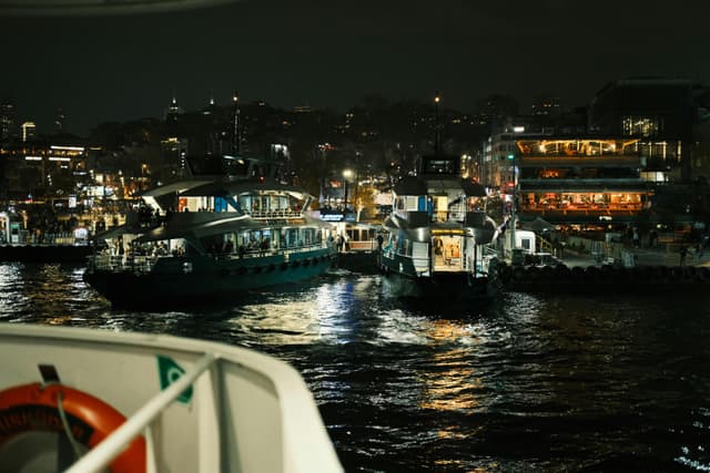 Illuminated boats in a lively harbor at night, showcasing vibrant city nightlife.