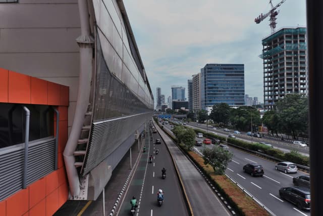 Daytime cityscape of a busy Jakarta street with skyscrapers and vehicles.