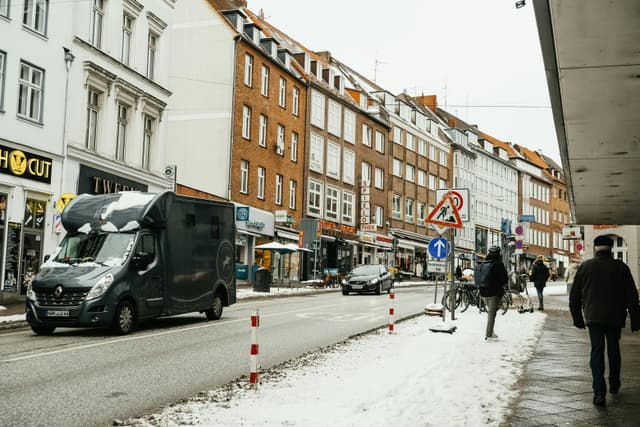 Urban winter scene with pedestrians and vehicles on a snowy city street.