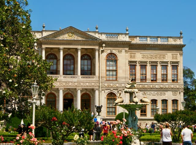 Elegant Ottoman architecture of a grand palace in Istanbul surrounded by vibrant gardens.