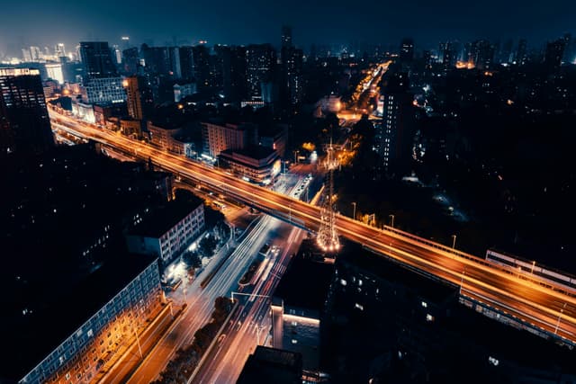 Aerial view of a bustling city at night with vibrant lights and busy streets.