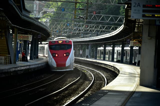A dynamic shot of a high-speed train arriving at a busy urban station, capturing motion and architecture.