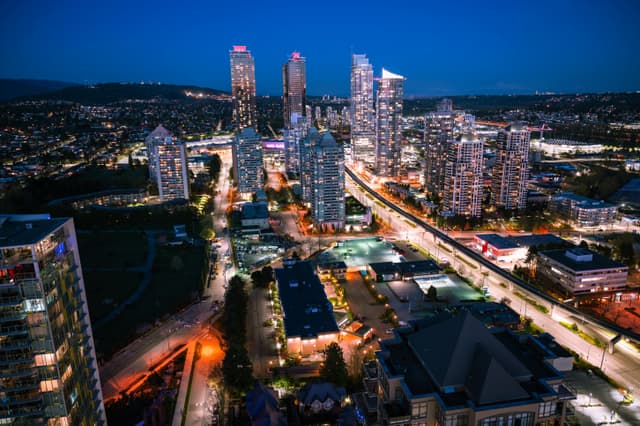 Bright city lights illuminating skyscrapers in a bustling urban skyline captured at night.