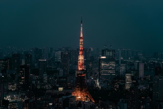 Stunning view of Tokyo Tower lit up at night, surrounded by the urban skyline of Minato City, Tokyo.