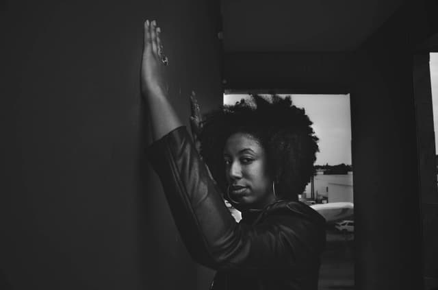 Black and white portrait of a confident woman against a city wall in an urban setting.