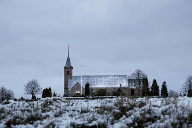 Chapel surrounded by snow in Randers, Denmark, on a cloudy winter day.