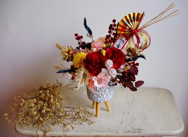 A vibrant flower arrangement with Asian-inspired decorations, perfect for celebrations.