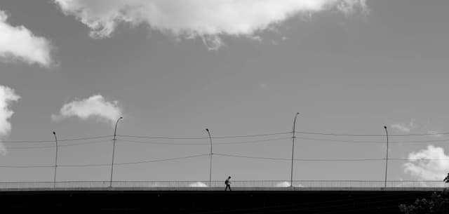 Monochrome image of a person silhouetted against the sky walking on a bridge in Teresina, Brazil.